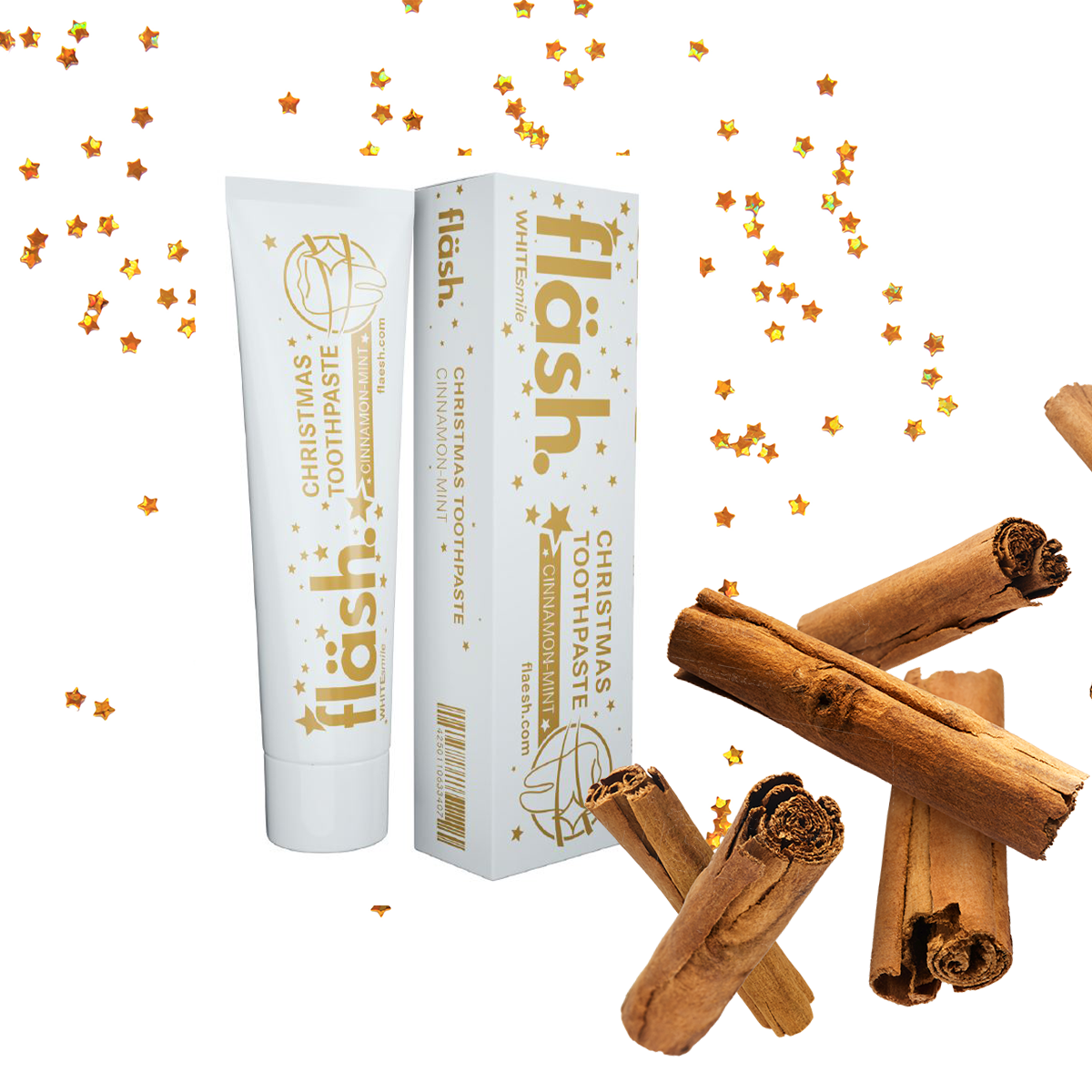 Auf weissem Hintergrund mit goldenen Sternchen steht die weiss-goldene Weihnachtsedition der fläsh Zahnpasta mit Zimt-Geschmack. Passend dazu sind im Vordergrund mehrere Zimtstangen.