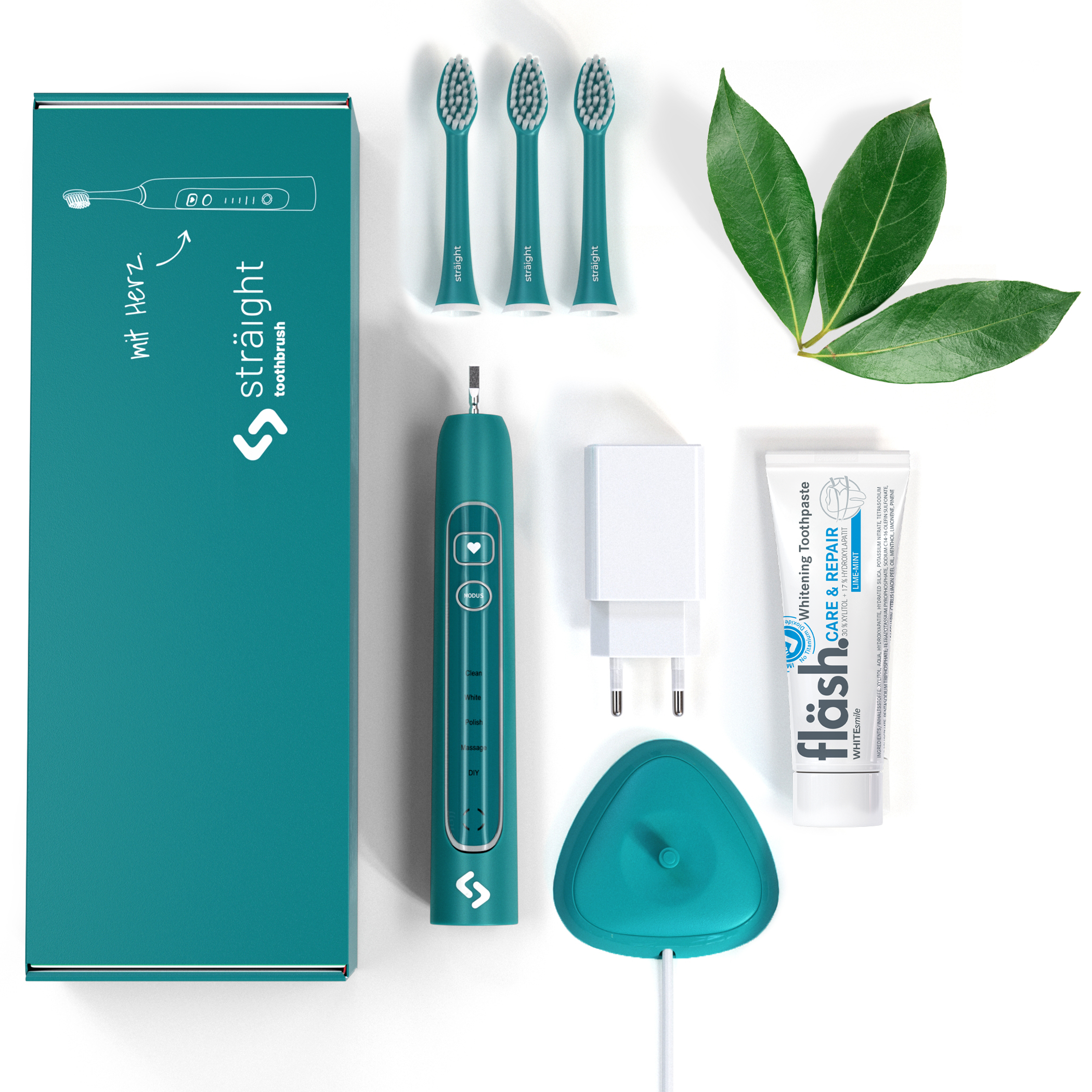 Auf weissem Hintergrund liegen alle im Lieferumfang enthaltenen Elemente der sträight Schallzahnbürste, Modell "Grün": der grüne Produktkarton, 3 Bürstenköpfe, der Zahnbürstengriff, die Ladestation mit Stecker sowie eine Tube fläsh Zahnpasta.