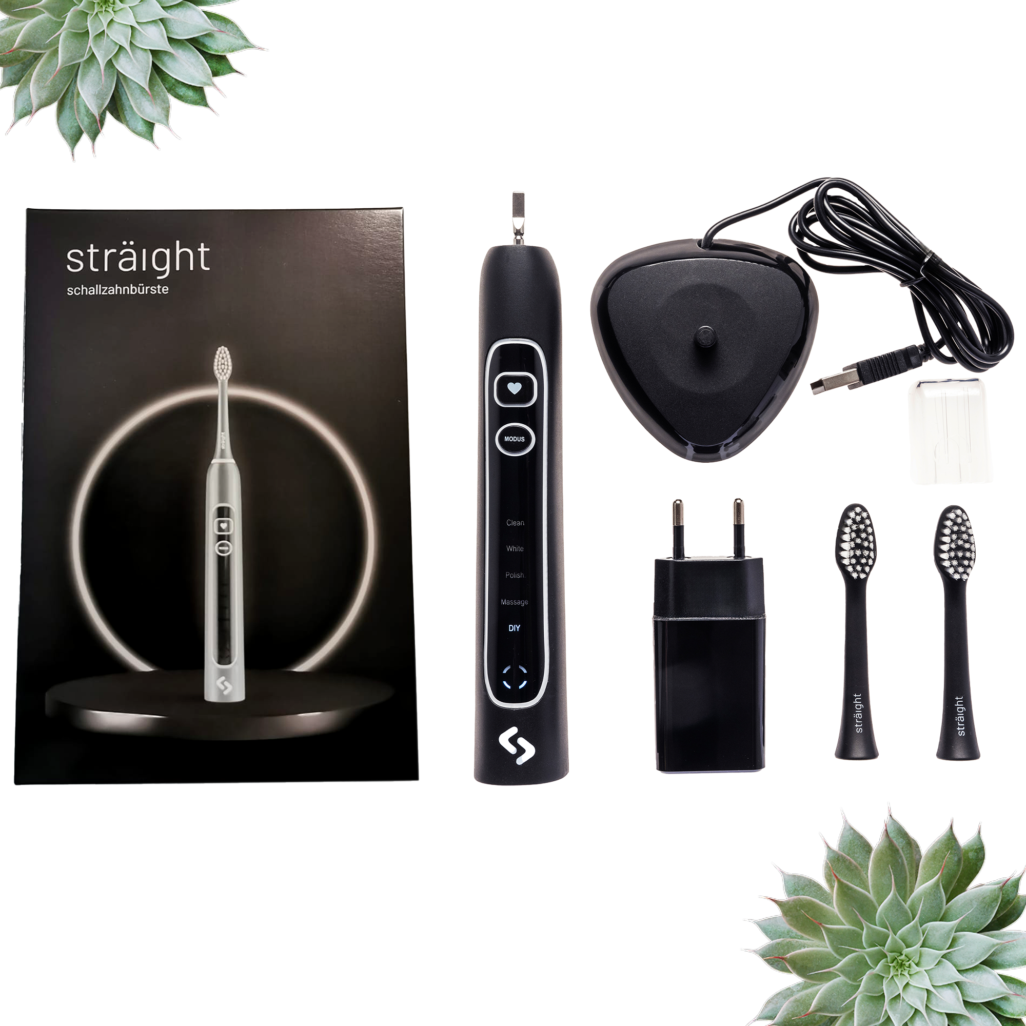 Auf weissem Hintergrund liegen alle im Lieferumfang enthaltenen Elemente der sträight Schallzahnbürste, Modell "Schwarz Light": der schwarze Produktkarton, 2 Bürstenköpfe, der Zahnbürstengriff, die Ladestation mit Stecker.