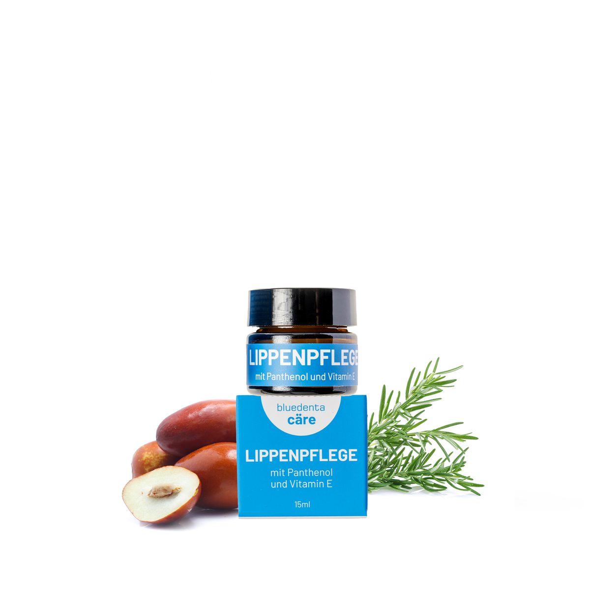 Auf weissem Hintergrund steht ein Glastiegel bluedenta cäre Lippenpflege, dahinter Rosmarinzweige  und Jojobanüssse als Symbol für die enthaltenen pflanzlichen Inhaltsstoffe.