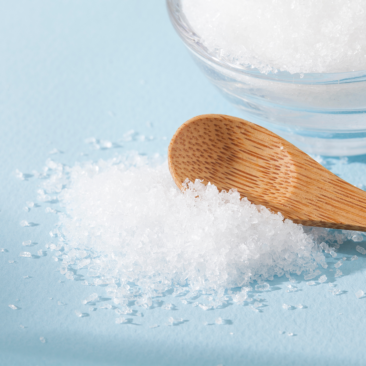 Eine Nahaufnahme von weissen Salzkristallen mit einem Holzlöffel.