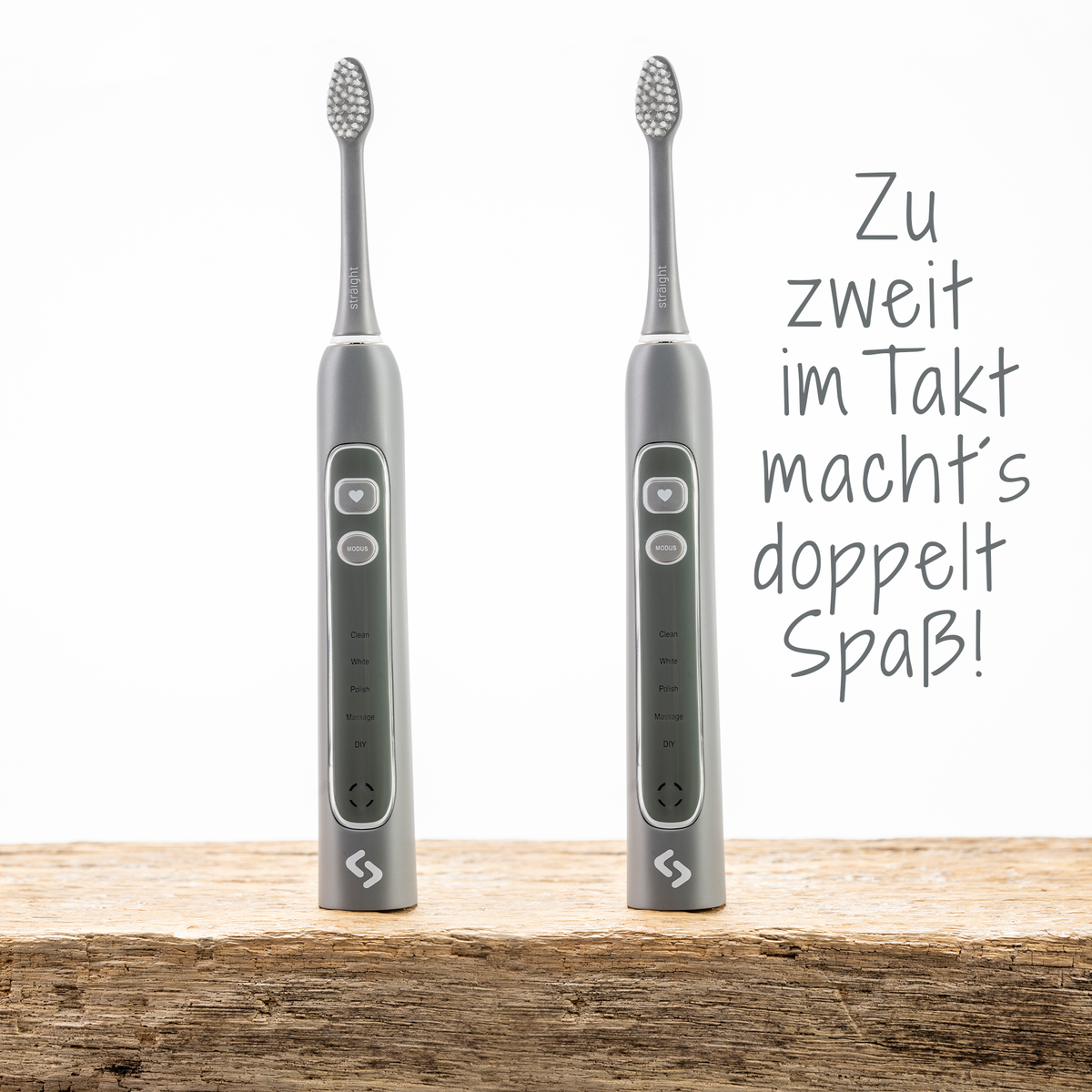 Zwei graue sträight Schallzahnbürsten stehen auf einer Holzplatte.