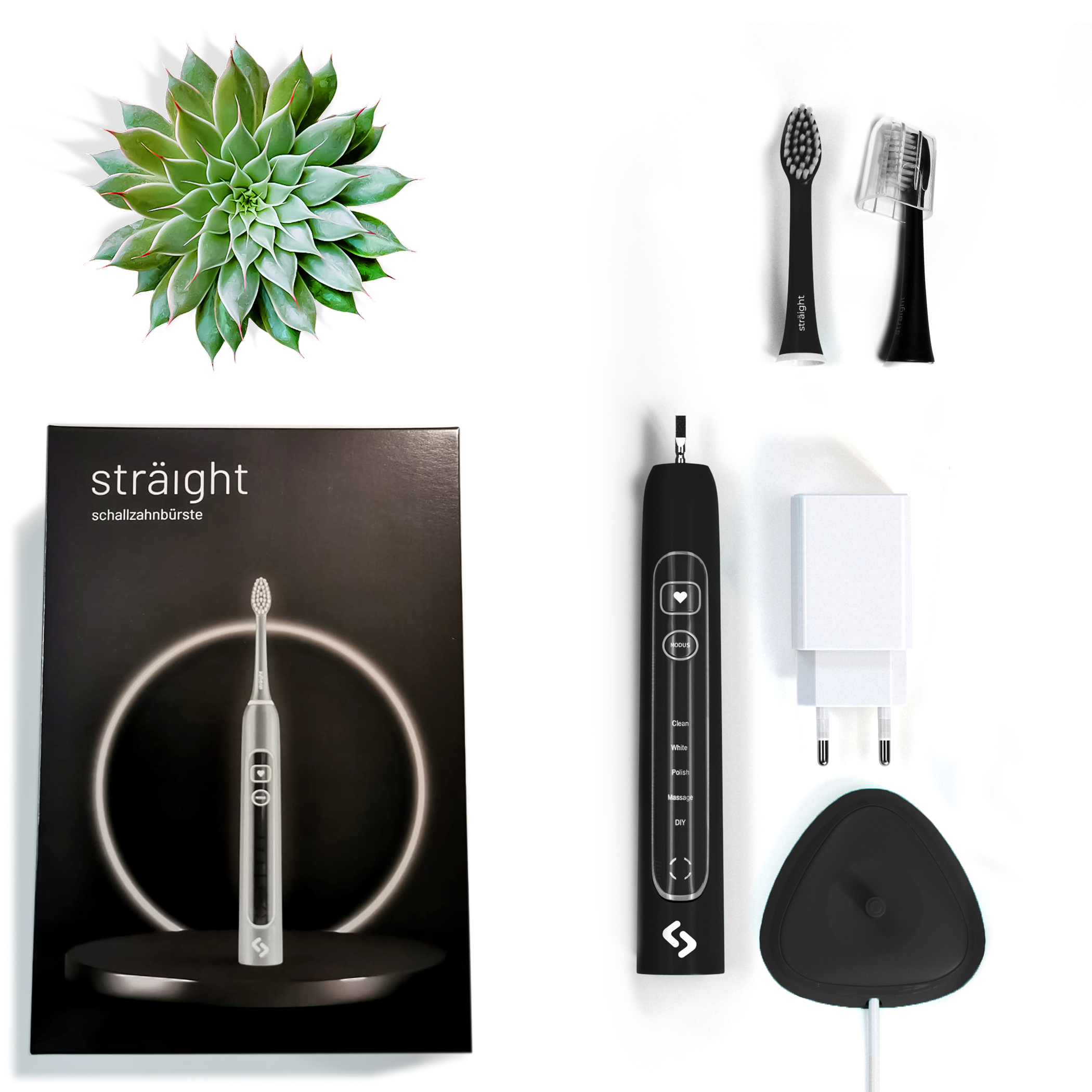 Auf weissem Hintergrund liegen alle im Lieferumfang enthaltenen Elemente der sträight Schallzahnbürste, Modell "Schwarz Light": der schwarze Produktkarton, 2 Bürstenköpfe, der Zahnbürstengriff, die Ladestation mit Stecker.