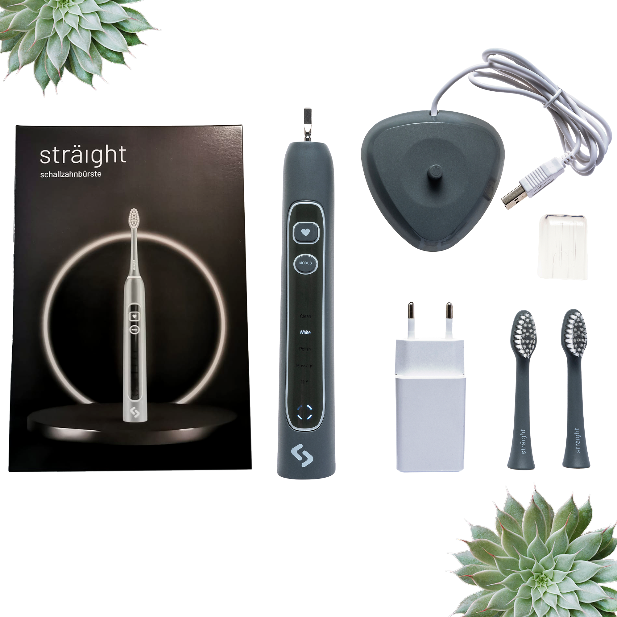 Auf weissem Hintergrund liegen alle im Lieferumfang enthaltenen Elemente der sträight Schallzahnbürste, Modell "Grau Light": der schwarze Produktkarton, 2 Bürstenköpfe, der Zahnbürstengriff, die Ladestation mit Stecker.